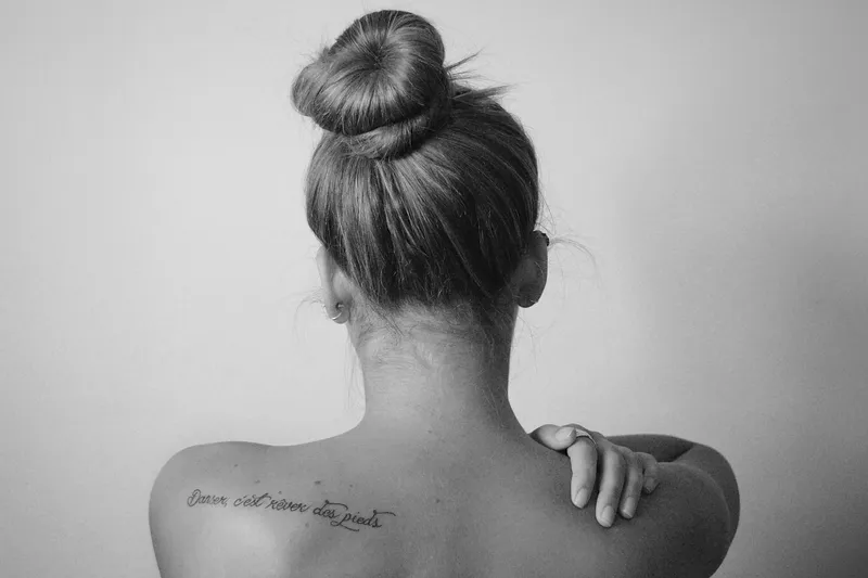 mulher com tatuagem nas costas e mão no ombro em referência à tatuagem e autoestima