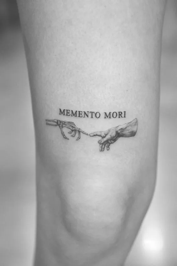 Tatuagem memento mori, onde duas mãos se tocam através dos indicadores, uma mão é esquelética e a outra é comum.