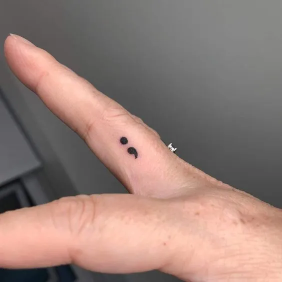 Tatuagem de ponto e vírgula no dedo