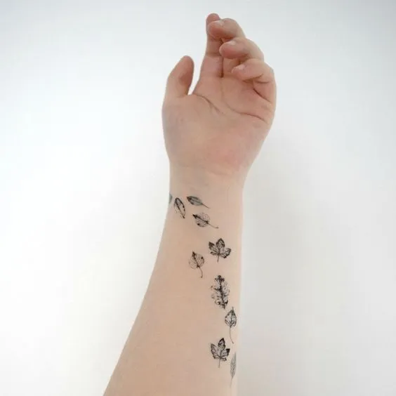 Tatuagem no antebraço de folhas caindo