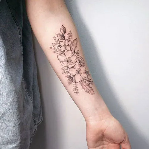 Tatuagem de flores em braço feminino