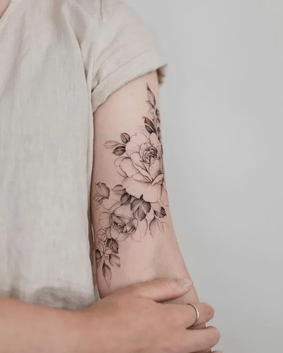 Tatuagem no bíceps de flores delicadas