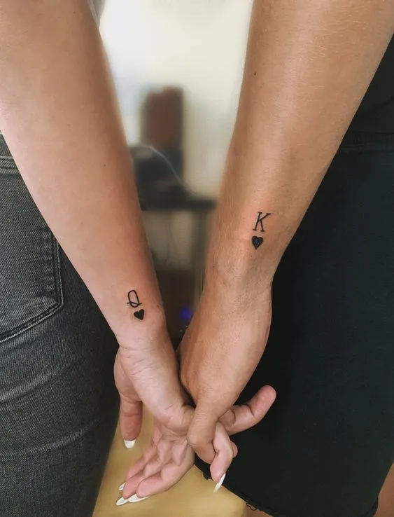 Tatuagem de casal com corações e as iniciais K e Q (rei e rainha)