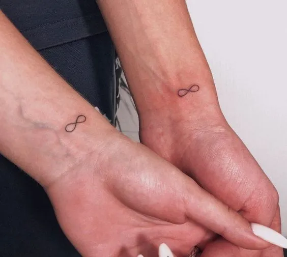 Tatuagem de casal com símbolos do infinito no pulso