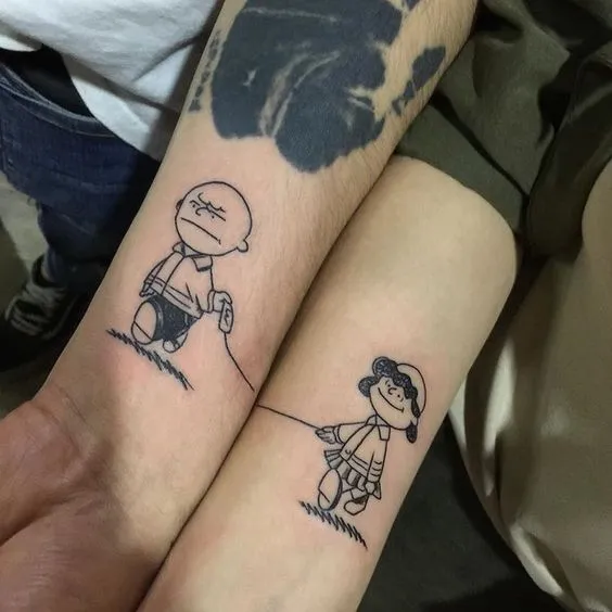 Tatuagem de casal nos braços do desenho Charlie Brown