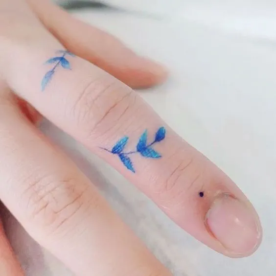 tatuagem delicada de flor azul no dedo