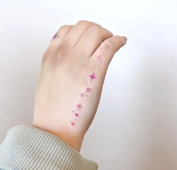 tatuagem minimalista de estrelinhas violetas na lateral da mão