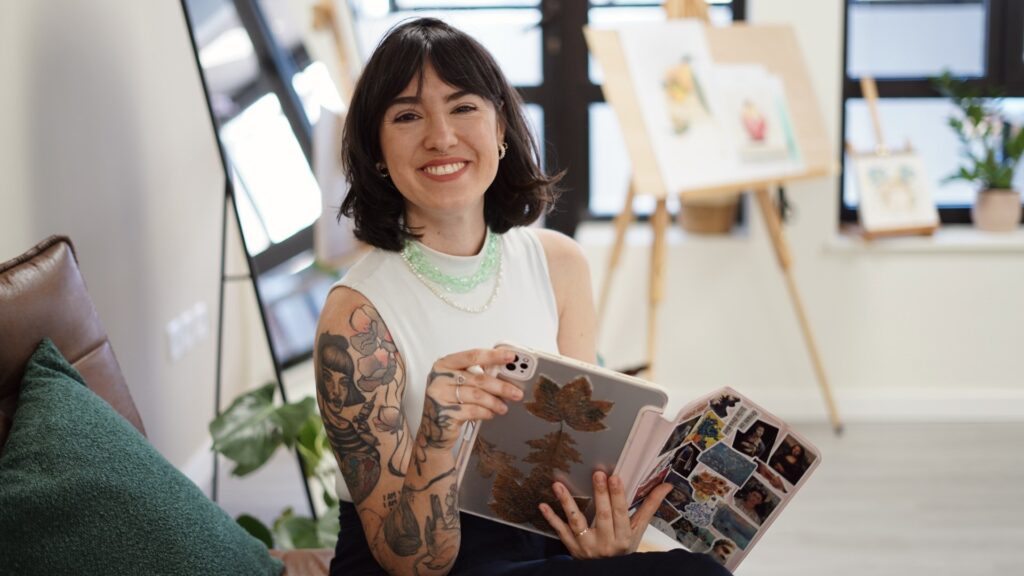 Gi Bianco, artiste tatoueur fine line à Porto Portugal, souriante avec une tablette de designs